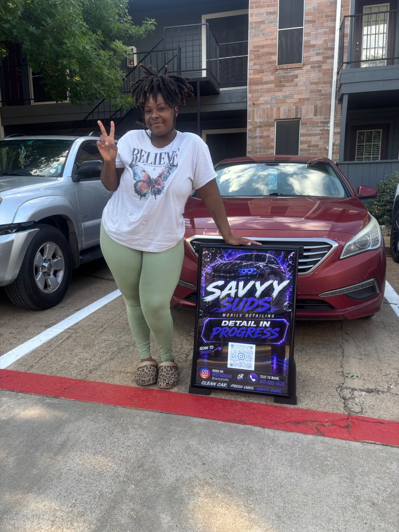 Savannah, founder of SavyySuds Mobile Detailing, with her Detail In Progress sign